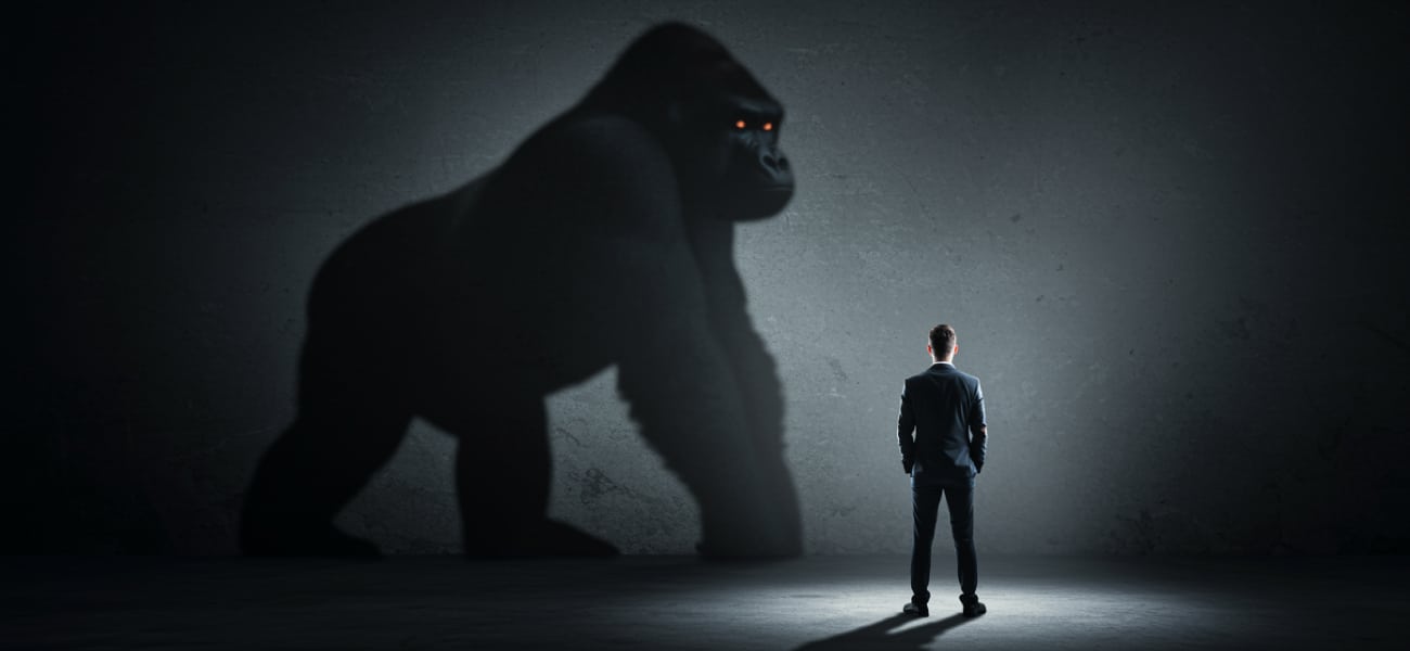 Small business founder standing in front of large gorilla shadow symbolizing intimidating market leaders